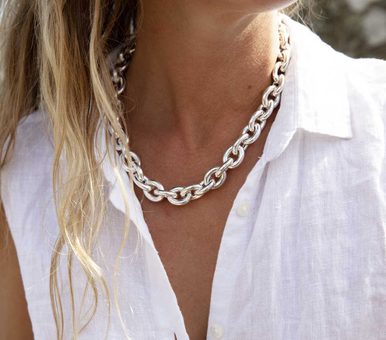 Tjej som bär ett chunky kedjehalsband i glänsande vitt silver.