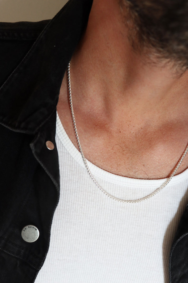 Man som bär en silverkedja runt halsen.