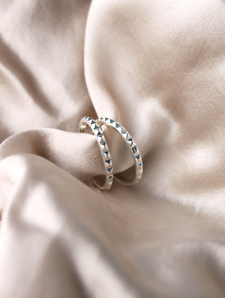 Silverörhängen med ringar som har små nitar längs med ringen.