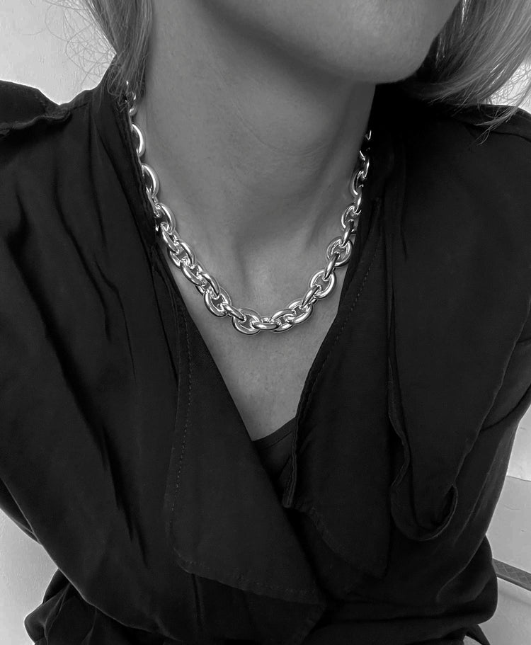 Kvinna som bär en bred silverkedja runt halsen.