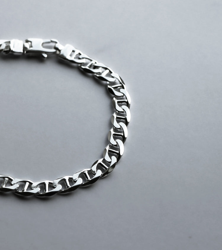 Närbild på armband med kedja som har facettslipade länkar som reflekterar ljuset.