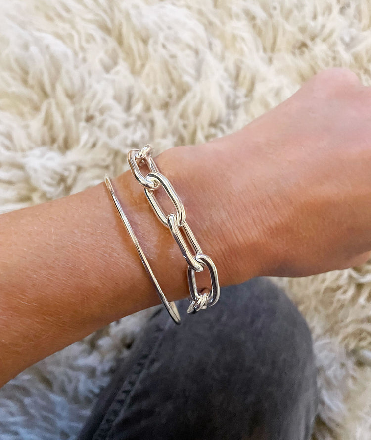 Närbild på en silverkedja med stora länkar som bärs tillsammans med en smal armring.