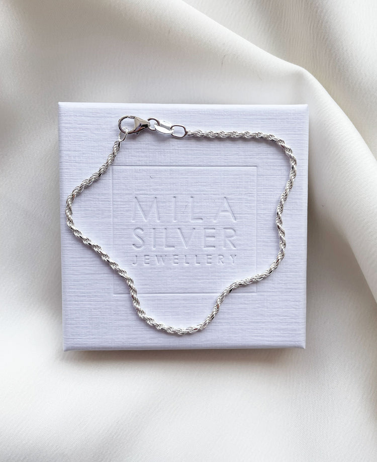 Ett silverarmband med twistad silverkedja placerad på en smyckesask från Mila Silver