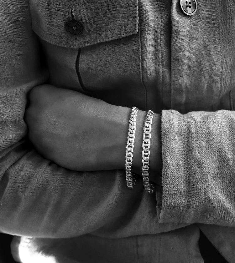 Man som bär två kedjearmband i kombination. En pansarkedja och en ankarkedja i äkta silver.