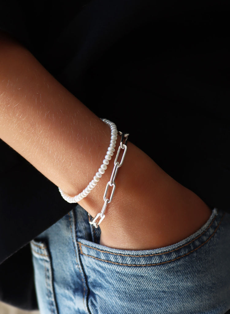 Silverarmband med kedja / Paperclip som bärs med ett pärlarmband med små pärlor.