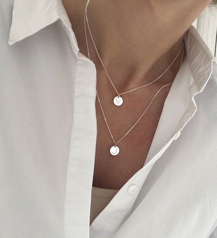 Tjej bär bokstavshalsband i silver.