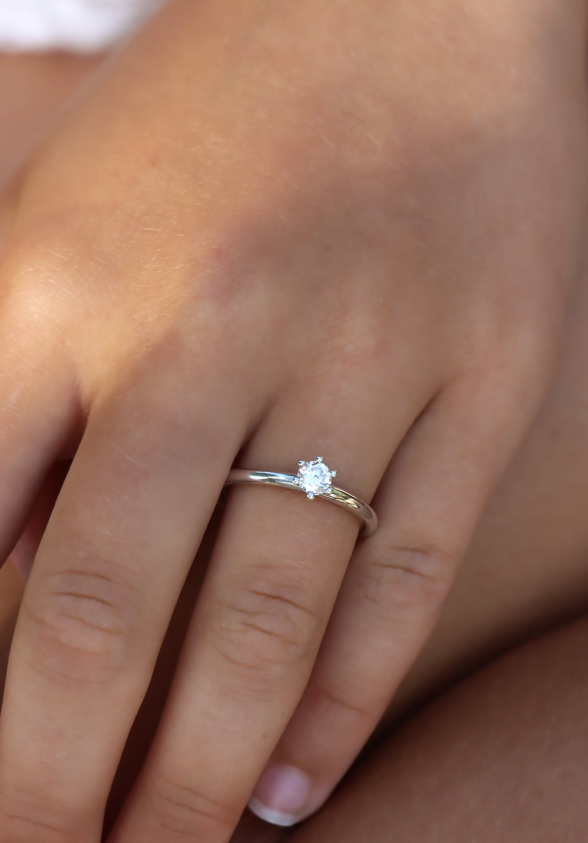 Tjej som bär en diamantring i silver med 0,25 ct rund diamant. Vigsel- eller förlovningsring.