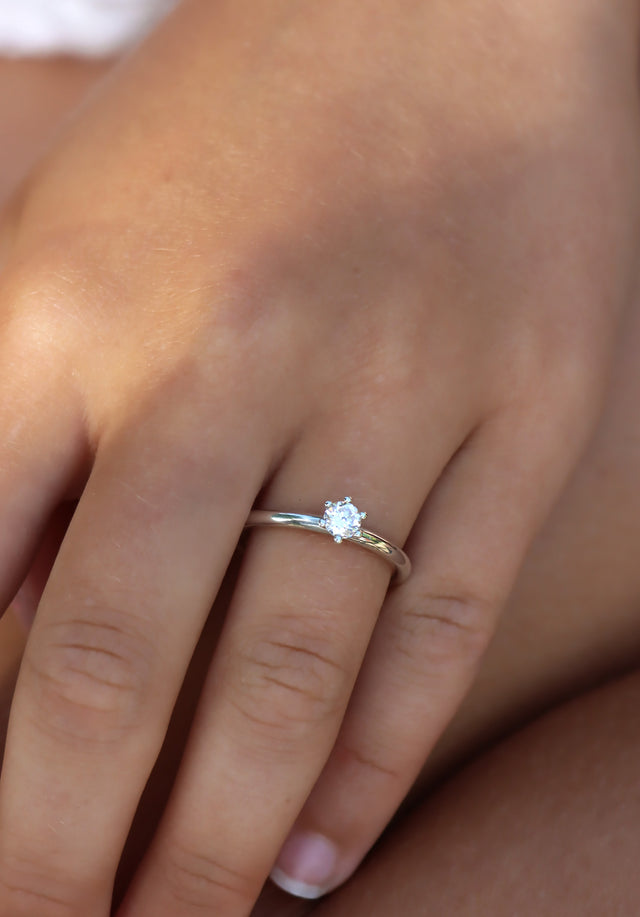 Tjej som bÀr en diamantring i silver med 0,25 ct rund diamant. Vigsel- eller förlovningsring.