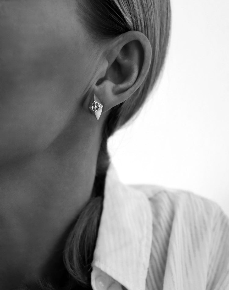 Kvinna som bär silverörhängen med spetsar.