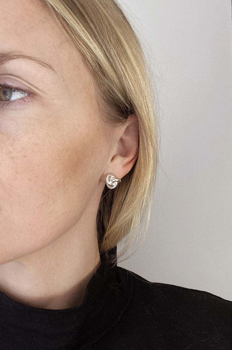 Tjej som bÀr örhÀngen med knutar i silver.