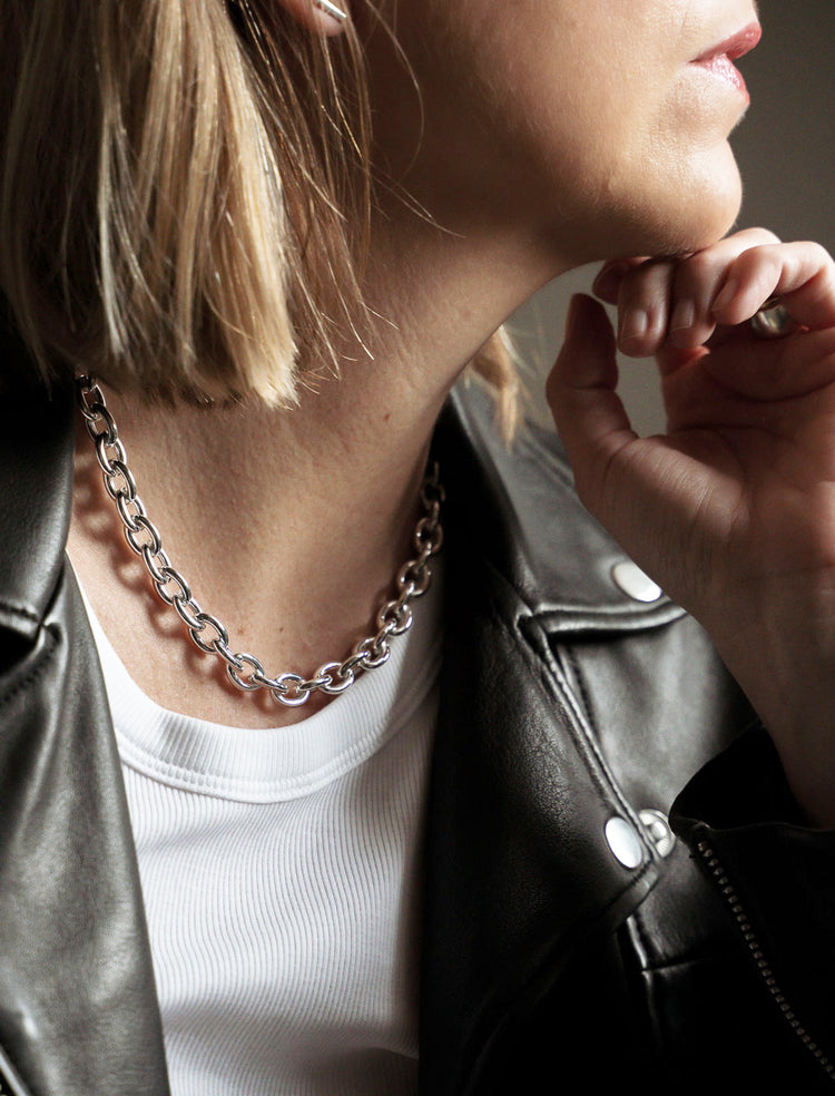 Tjej som bär ett chunky kedjehalsband i silver.