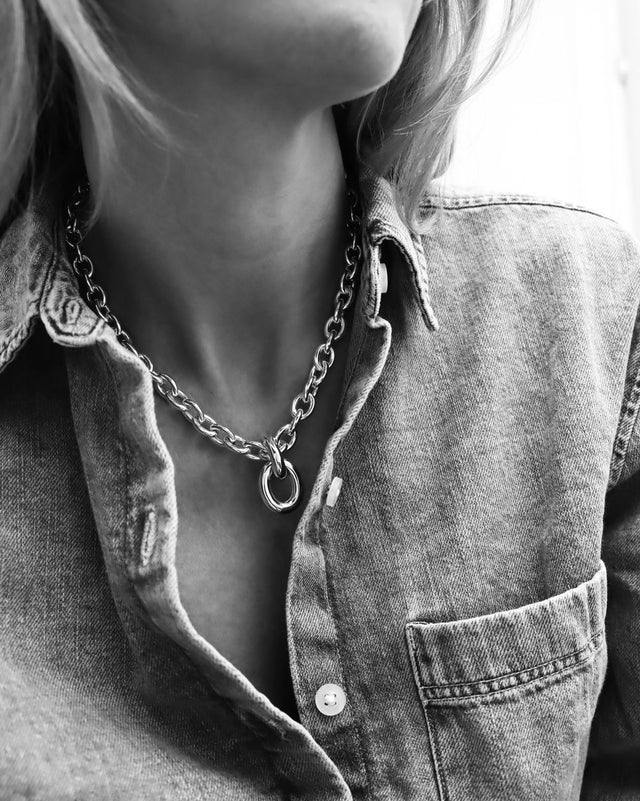 Kvinna som bär ett chunky kedjehalsband i silver.