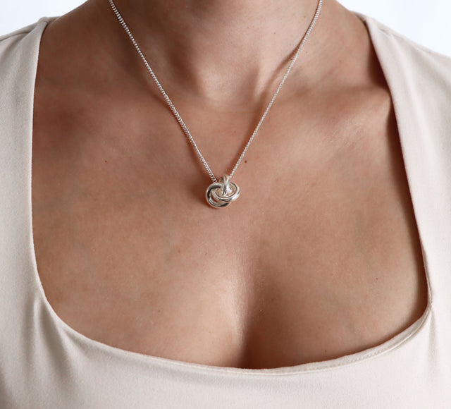 tjej som bär ett kort silverhalsband med en stor knut i pansarkedja
