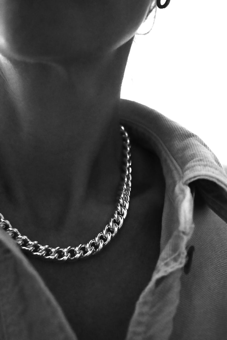 Kvinna som bär ett chunky halsband med bred silverkedja av modell Pansarkedja.