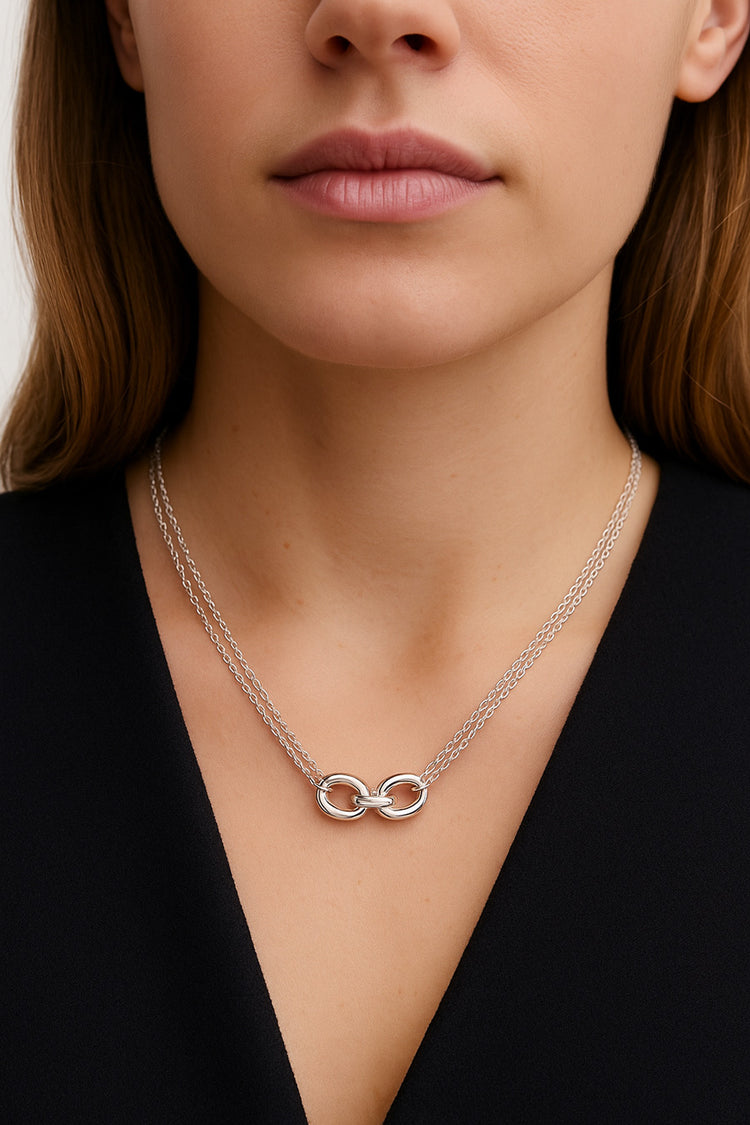 kvinna som bär ett silverhalsband med tre länkar i dubbla kedjor.