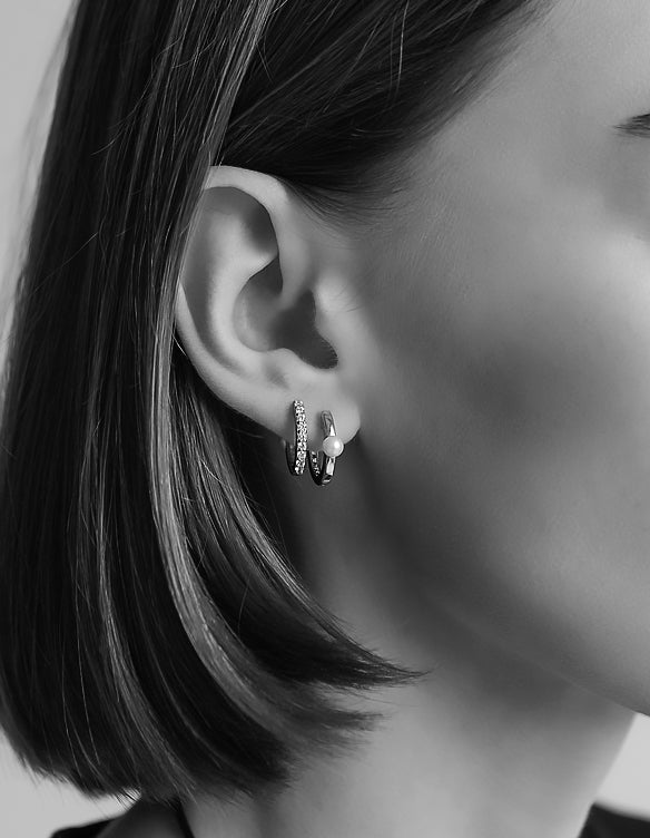 Tjej som bär två små hoop ringar i samma öra med gnistrande stenar och pärla.