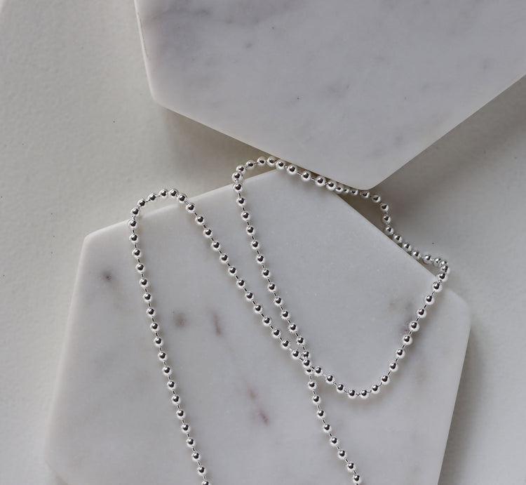 en kulkedja i silver som ligger på två marmor block.