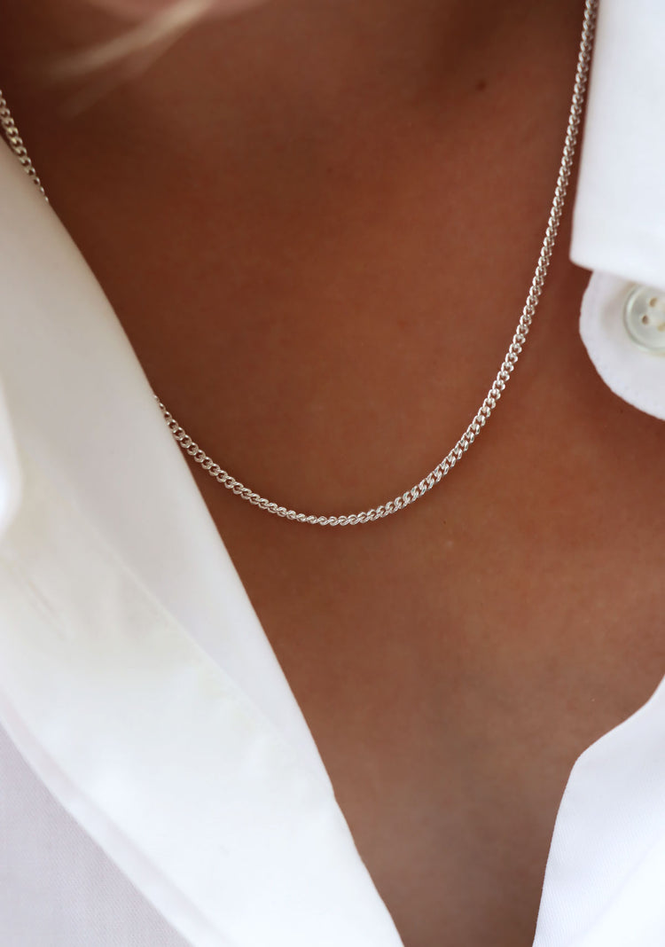 Kvinna som bär ett kedjehalsband i silver. Pansarkedja, längd 45 cm.