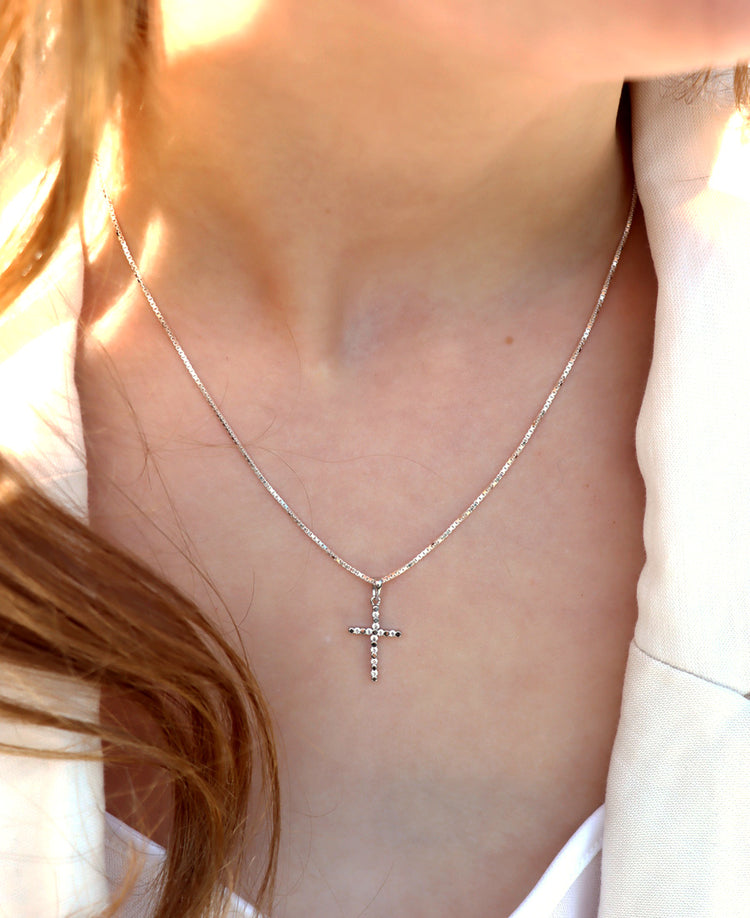 Tjej som bär ett silverhalsband med silverkors utsmyckat med kristaller.