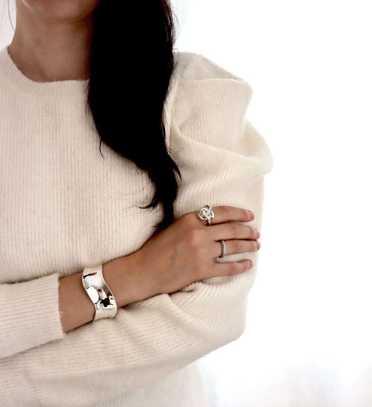 Tjej som bÀr ringar med stora silverkulor och ett brett cuff armband i silver.