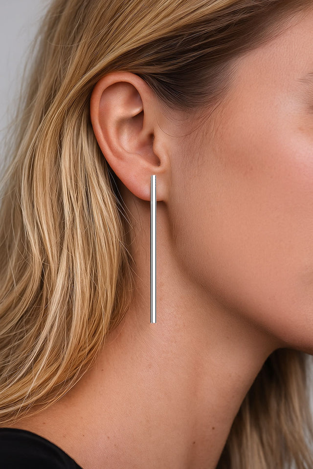 Tjej som bär långa hängande stavar i öronen