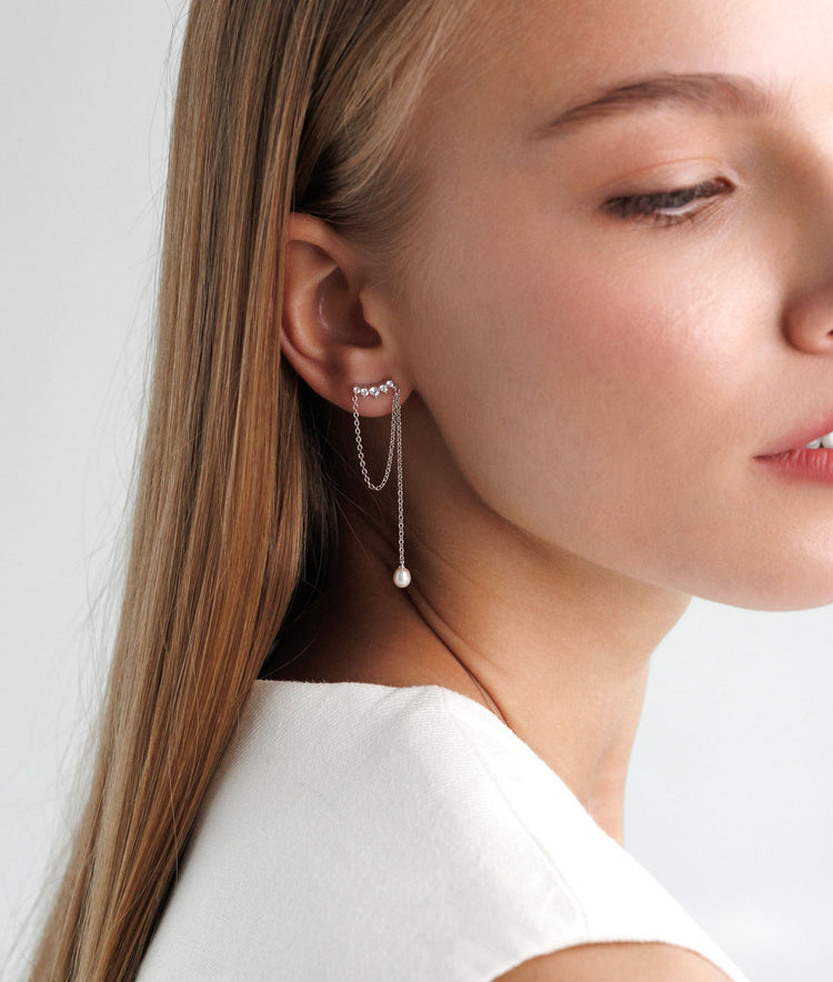 Tjej som bär hängande örhängen med stenar, kedjor och pärlor.