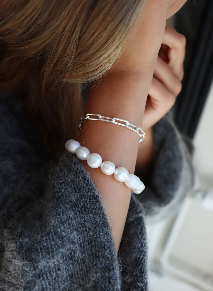 Tjej som bär ett pärlarmband med stora vita pärlor, barockpärlor.