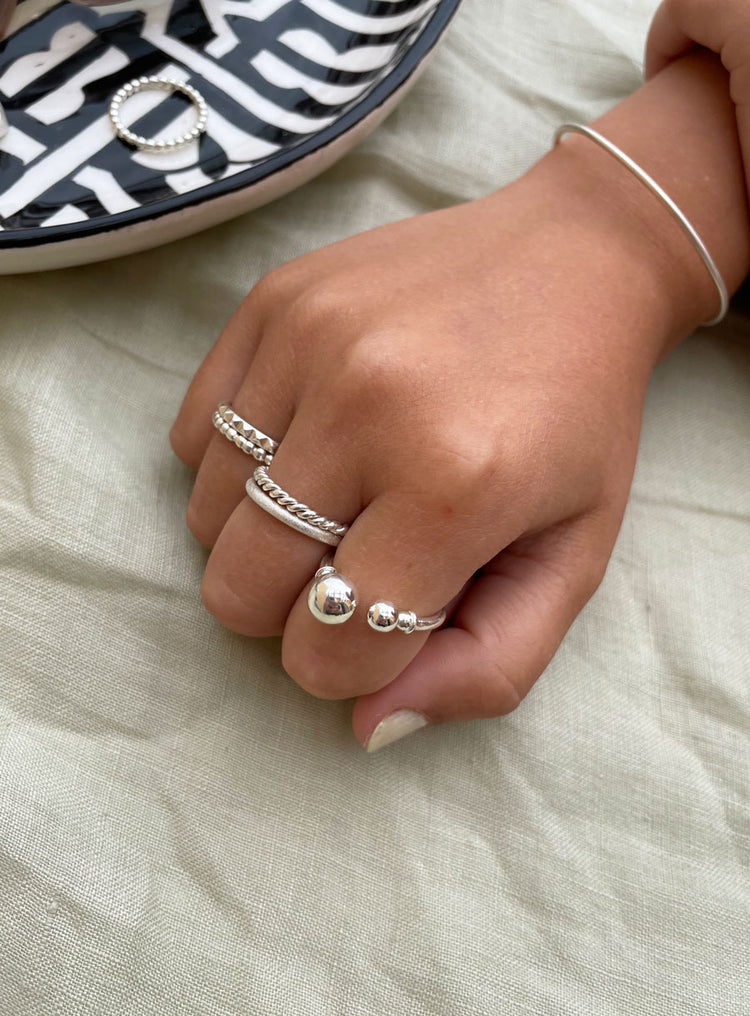 Öppen silverring med två kulor i olika storlekar, bärs på pekfingret. Kombinerat mer flera smala silverringar på de andra fingrarna.