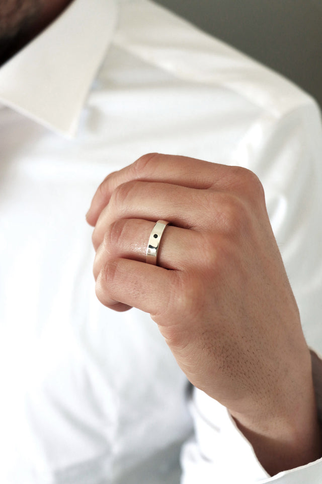 Man som bär silverring med svart diamant.