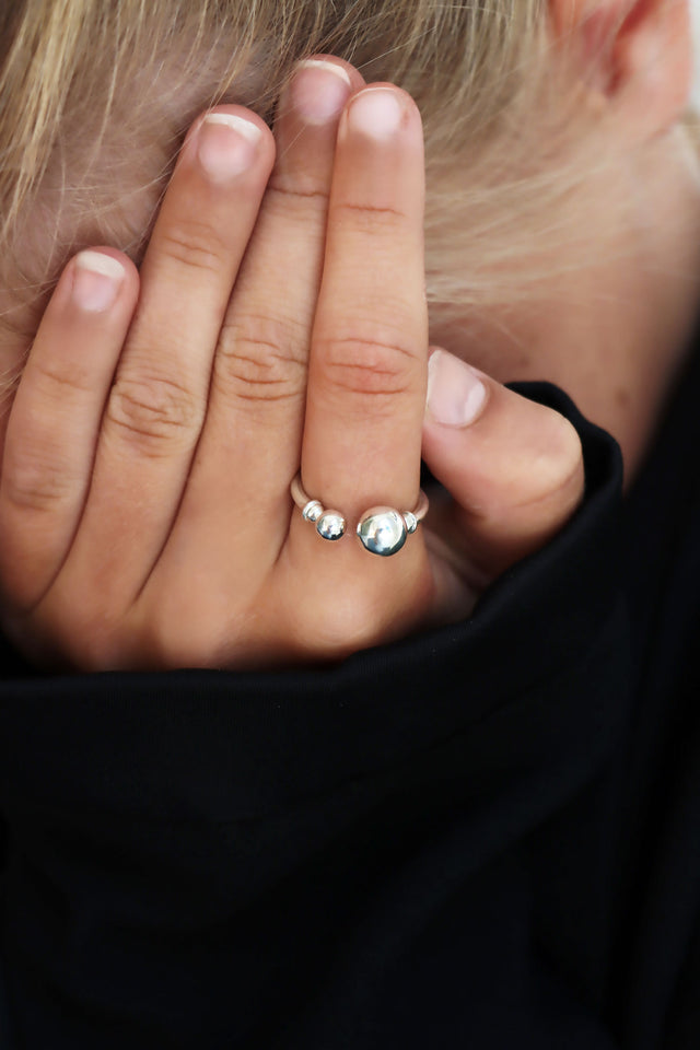 Tjej som bär en öppet silverring med kulor på pekfingret.