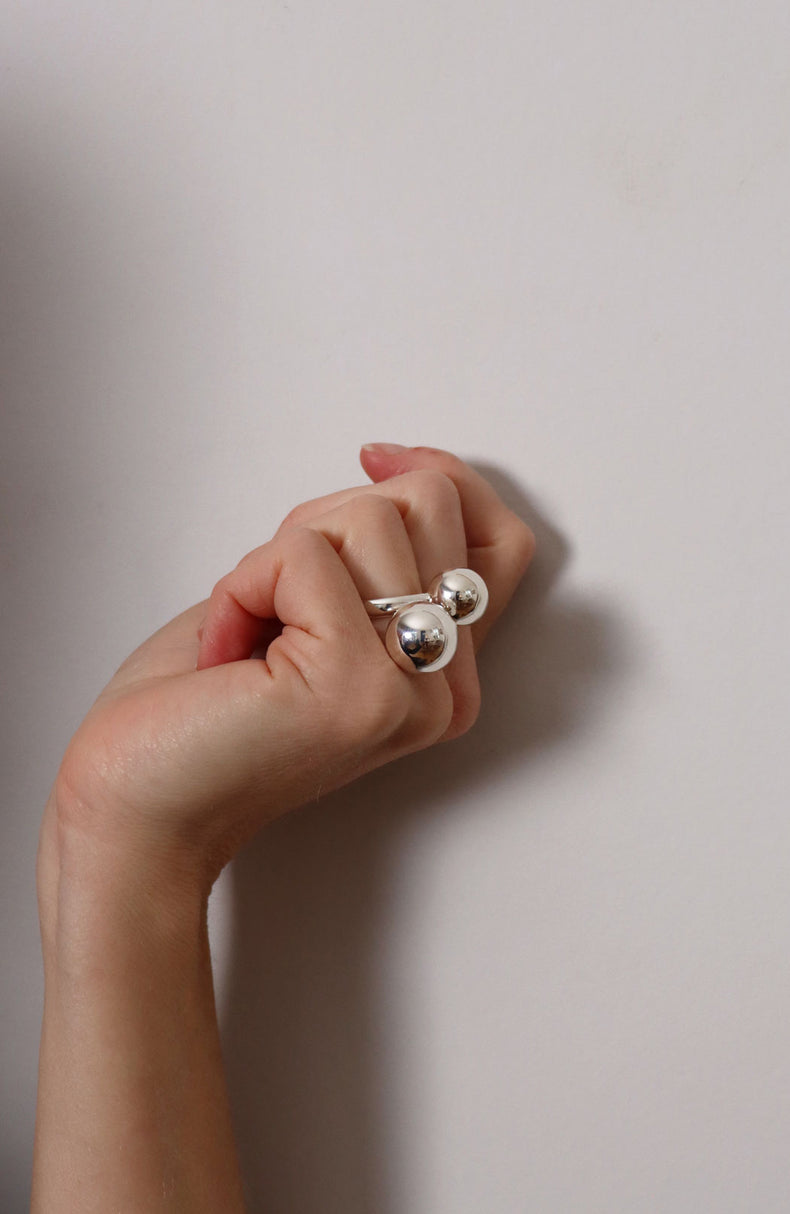 Tjej som bär en stor silverring med två silverkulor på långfingret.