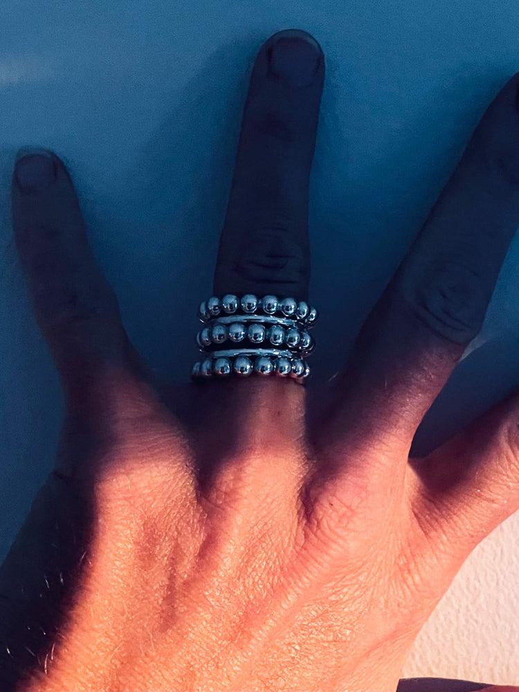 En bred ringkombination med tre ringar som har silverkulor.