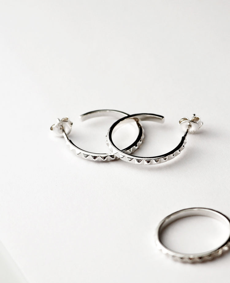 Silverörhängen med ringar som har små nitar längs med ringarna.