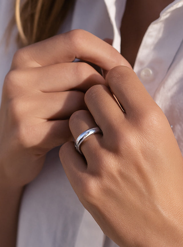 Tjej som bär en tjock silverring av blankt silver.