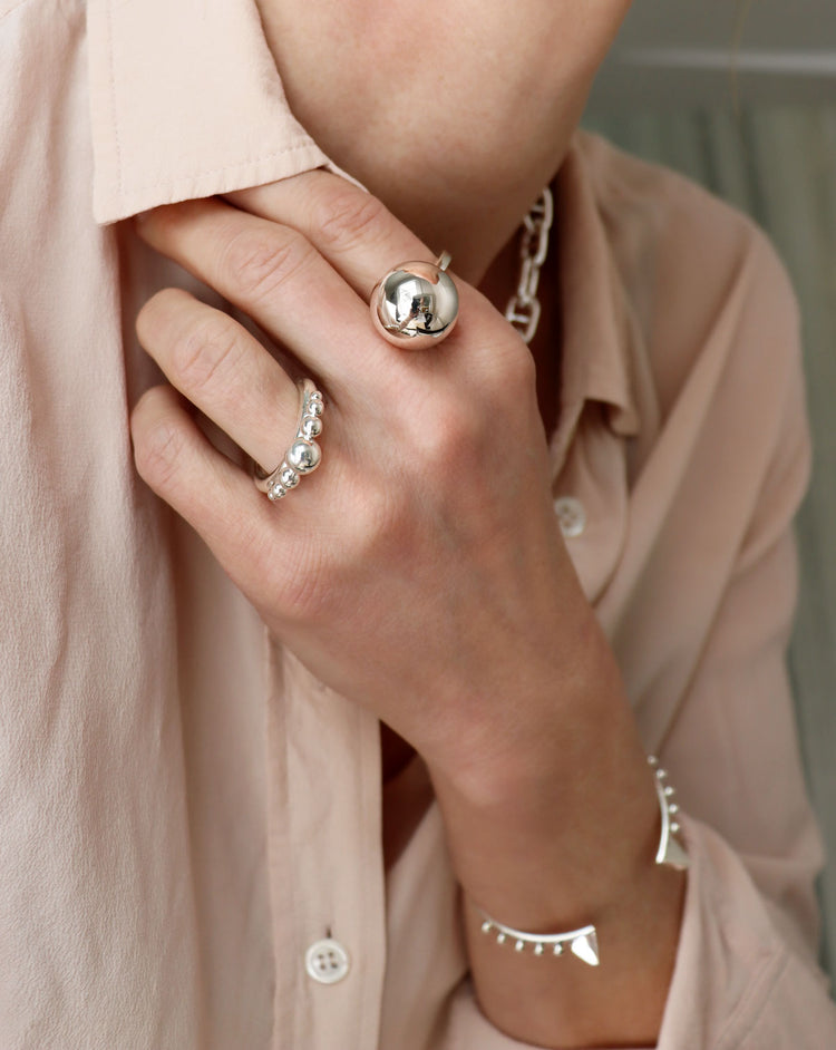 Tjej som bär två silverringar med kulor i olika storlekar.