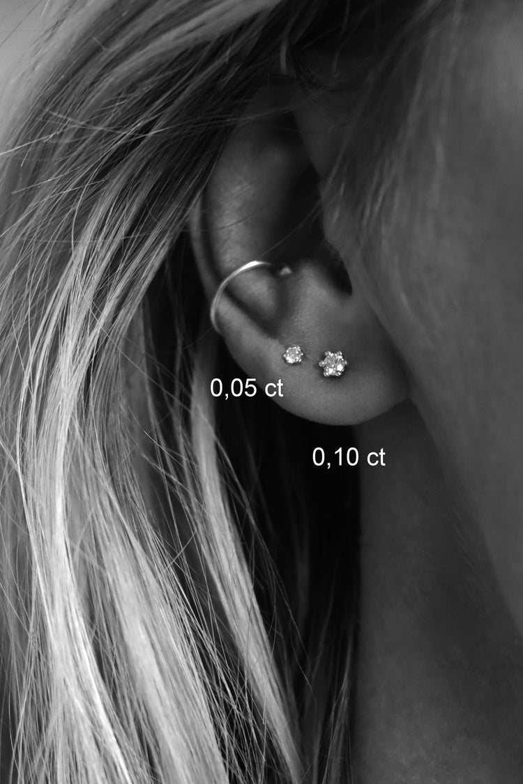 Tjej som bär två små diamantörhängen med 0,10 ct diamant och 0,5 ct diamant.