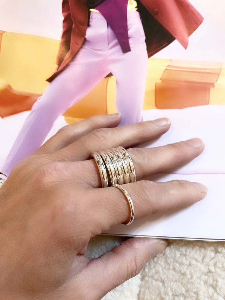 Bred ring stack med fyra tjocka silverringar som bärs på samma finger.