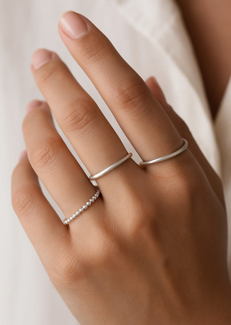 Tjej som bär smala silverringar på olika fingrar.