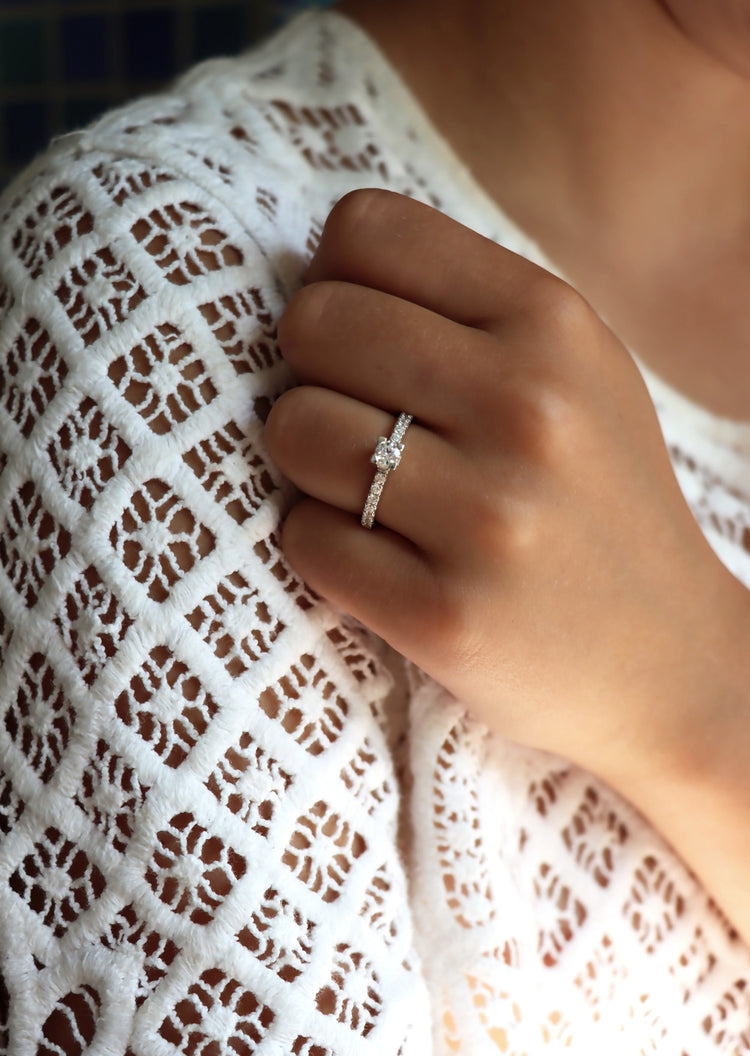 Tjej som bär en diamantring, modell solitärring med sidostenar som vigselring eller förlovningsring. Diamanten i mitten har fyrkantig fattning.