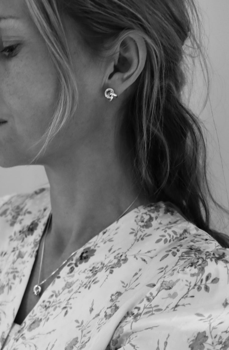 Tjej som bÀr örhÀngen med silverknutar och matchande halsband med knut.