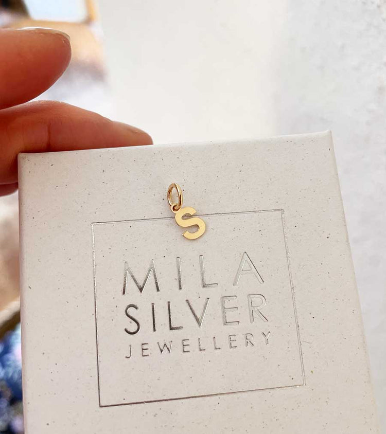 En bokstav i guld med ögla.