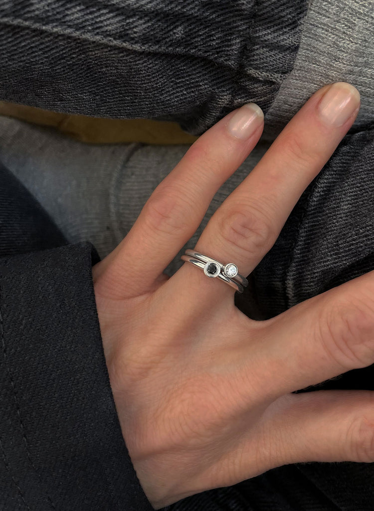 Två diamantringar i kombination. En med vit och en med svart diamant.