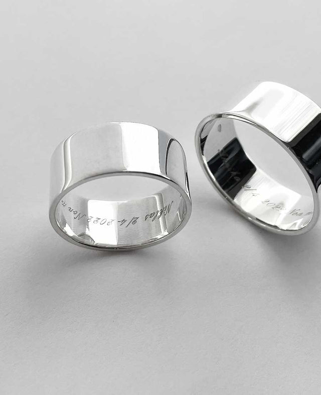 Två silverringar som har graverad text på insidan.
