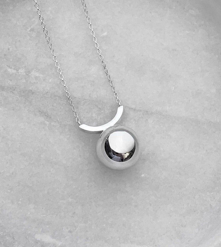 Halsband med en stor kula på en båge, fäst i en silverkedja.