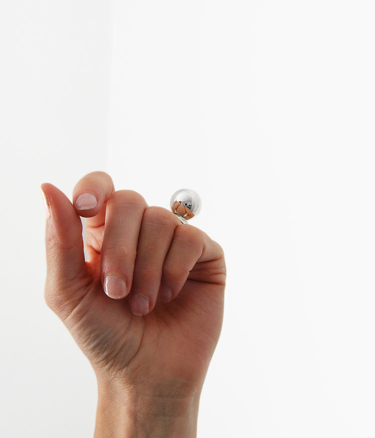 Hand med en silverring som har en stor silverkula som sticker upp.
