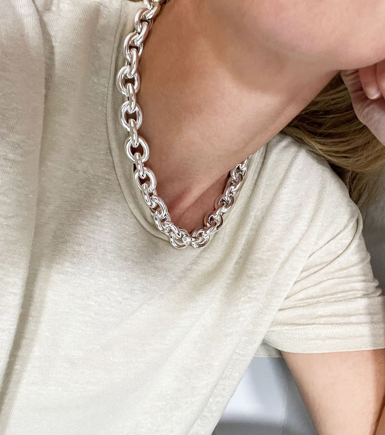 Tjej som bär en stor silverkedja runt halsen.