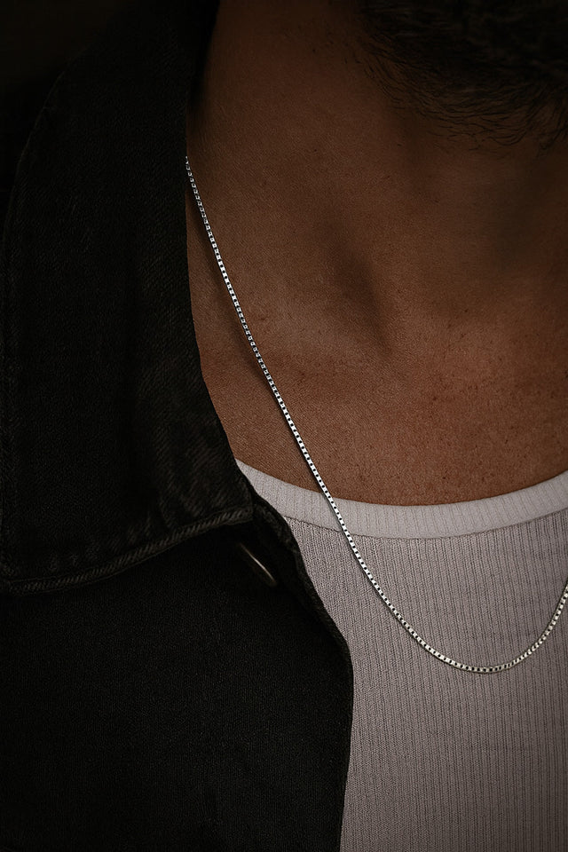 Man som bär ett silverhalsband med kedja. 