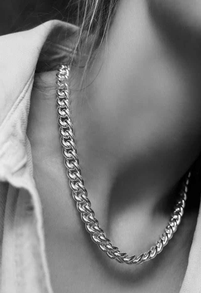 Kvinna som bär ett chunky halsband med tjock silverkedja. 