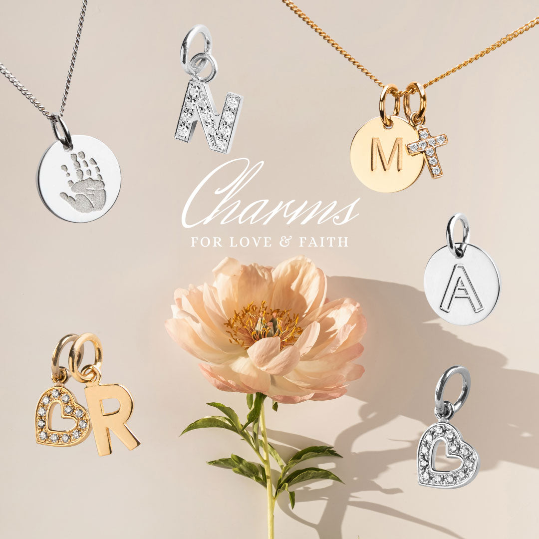Bild med flera berlocker i silver, guld och med diamanter placerade runt en blomma. Bokstavsberlocker och berlocker med handavtryck. 