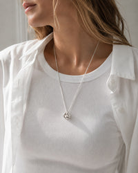 Kvinna som bär ett halsband med en silverknut i kedja.
